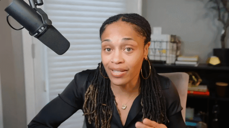 Presenter looking directly at camera, speaking with a focused expression; microphone visible at left.