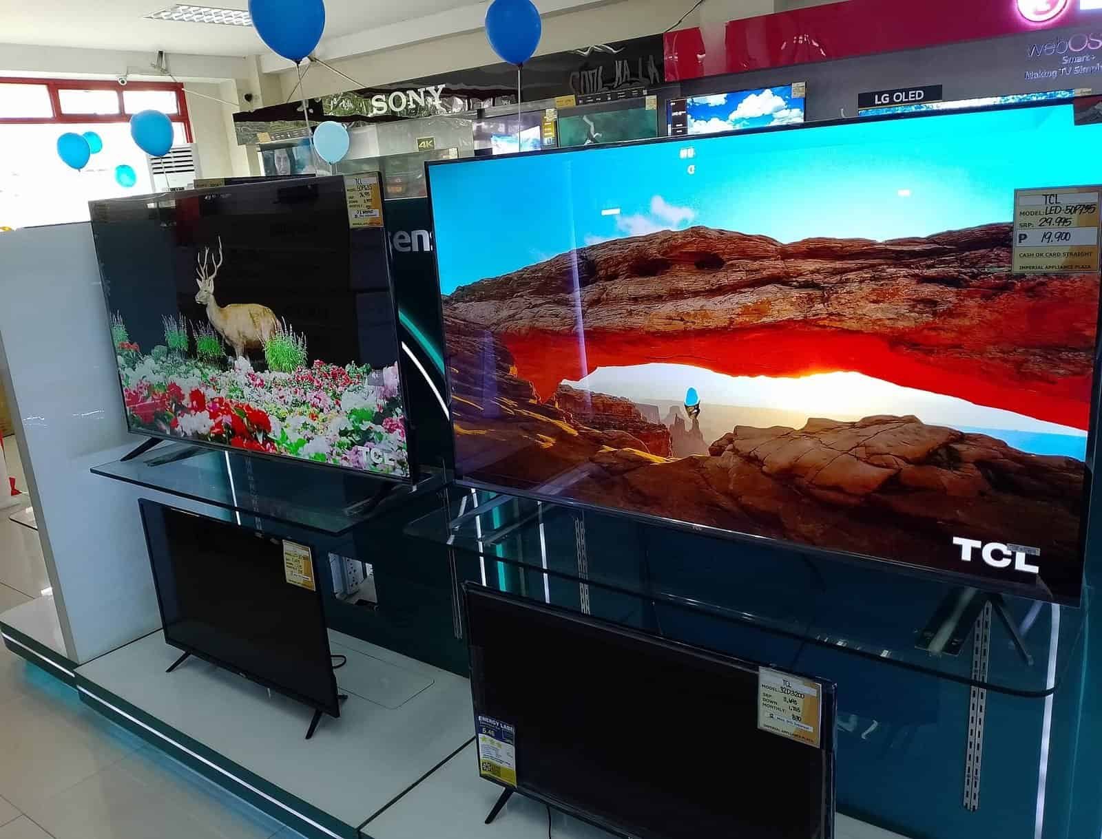 Row of large 4K TVs on display in an electronics store