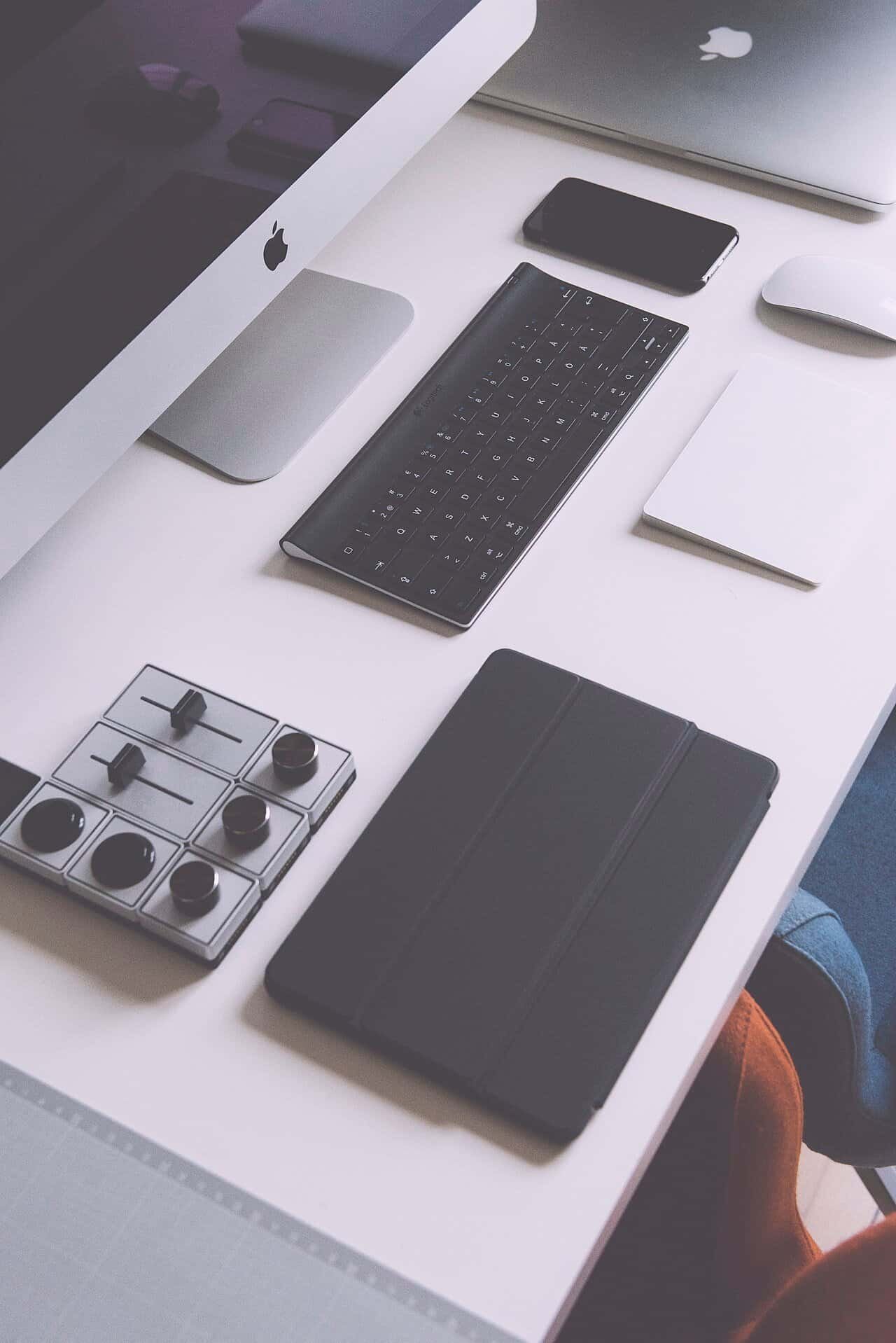 Smartphone, earbuds, watch and other gadgets arranged on a wooden desk