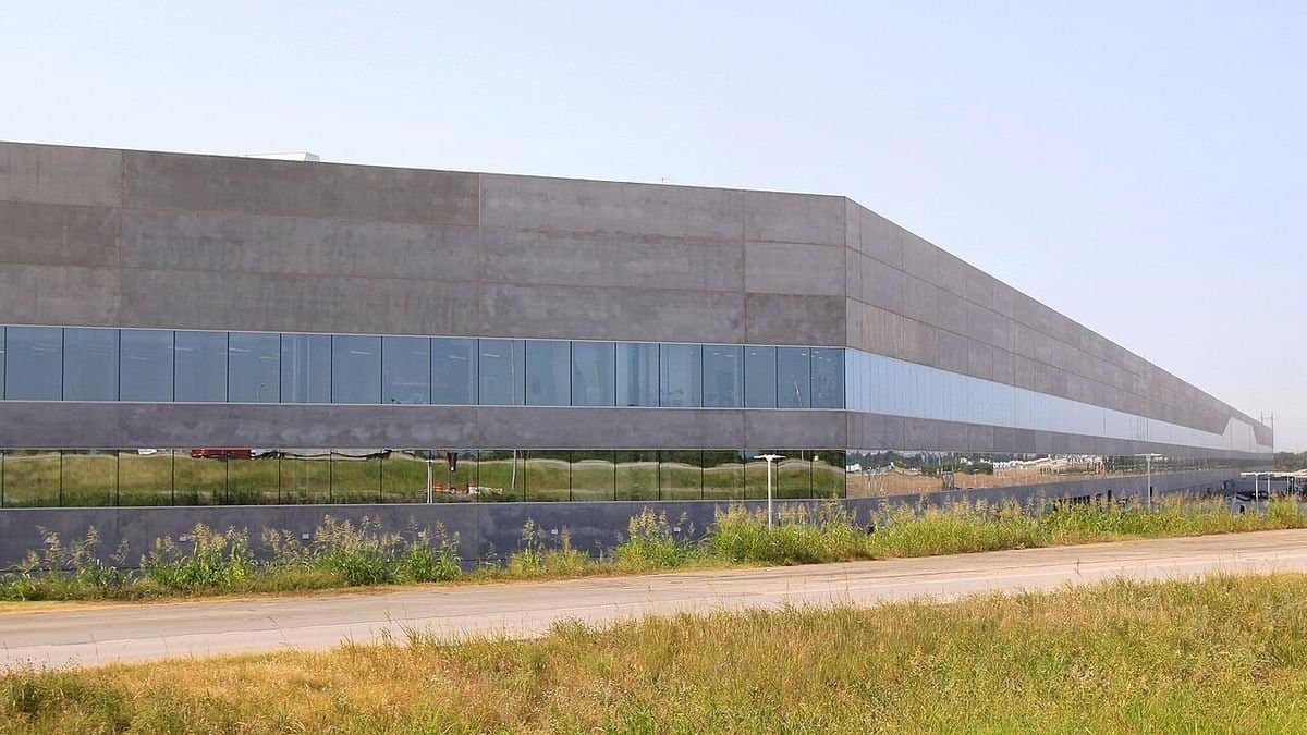Tesla Gigafactory Texas Building 1 near Austin, a long gray factory building behind a grassy field