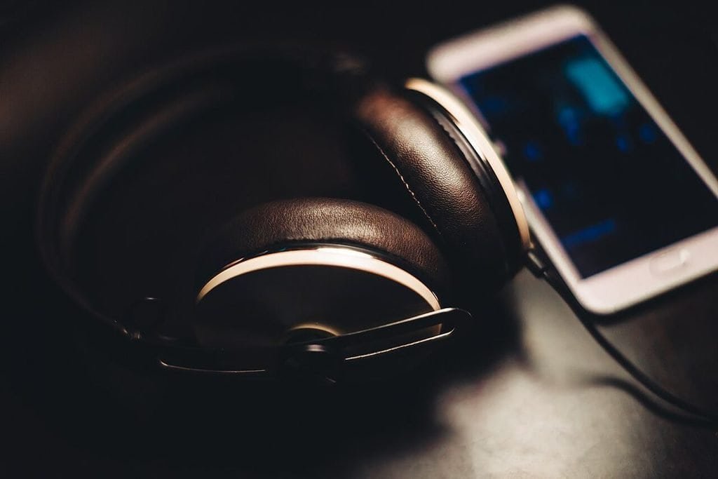 Over-ear headphones lying next to a smartphone on a dark surface