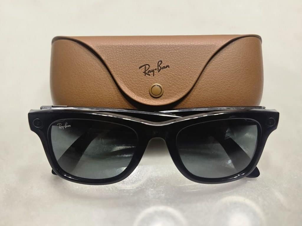 Black Ray-Ban Meta Gen 1 smart glasses in front of their brown charging case