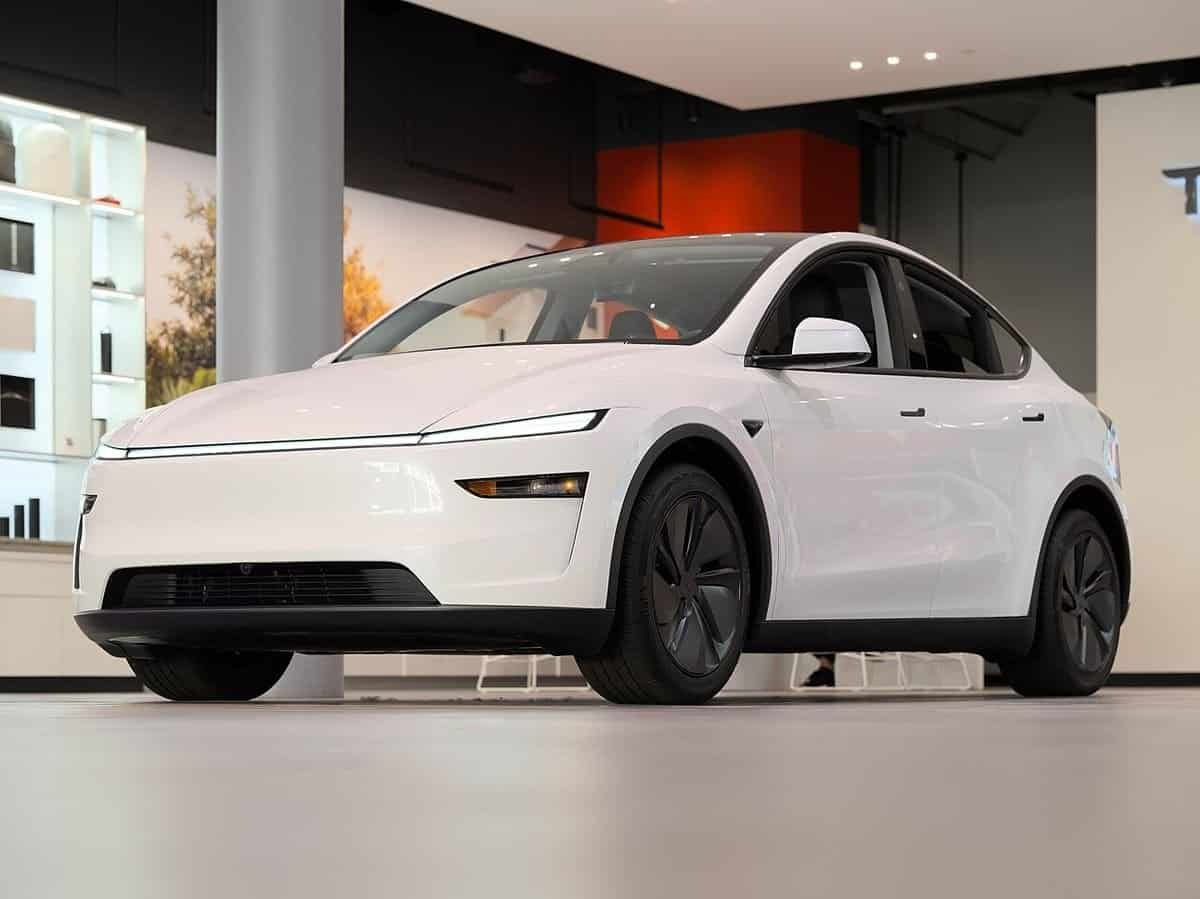 White 2025 Tesla Model Y on display inside a Tesla showroom