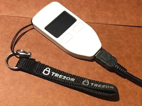 Button-style Trezor hardware wallet on a lanyard (item type photo, not the exact product)