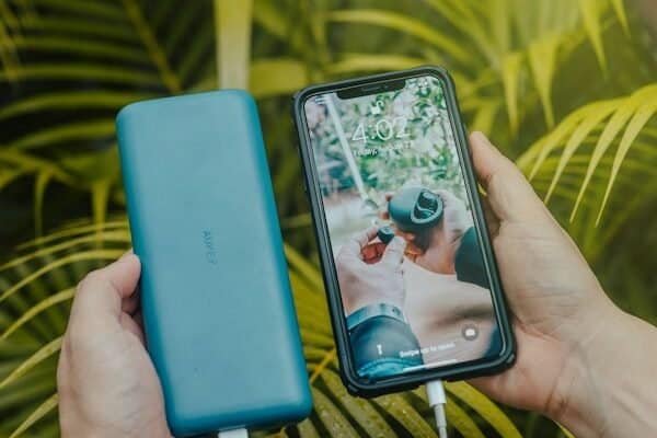 Black smartphone charging from a green portable power bank, close-up