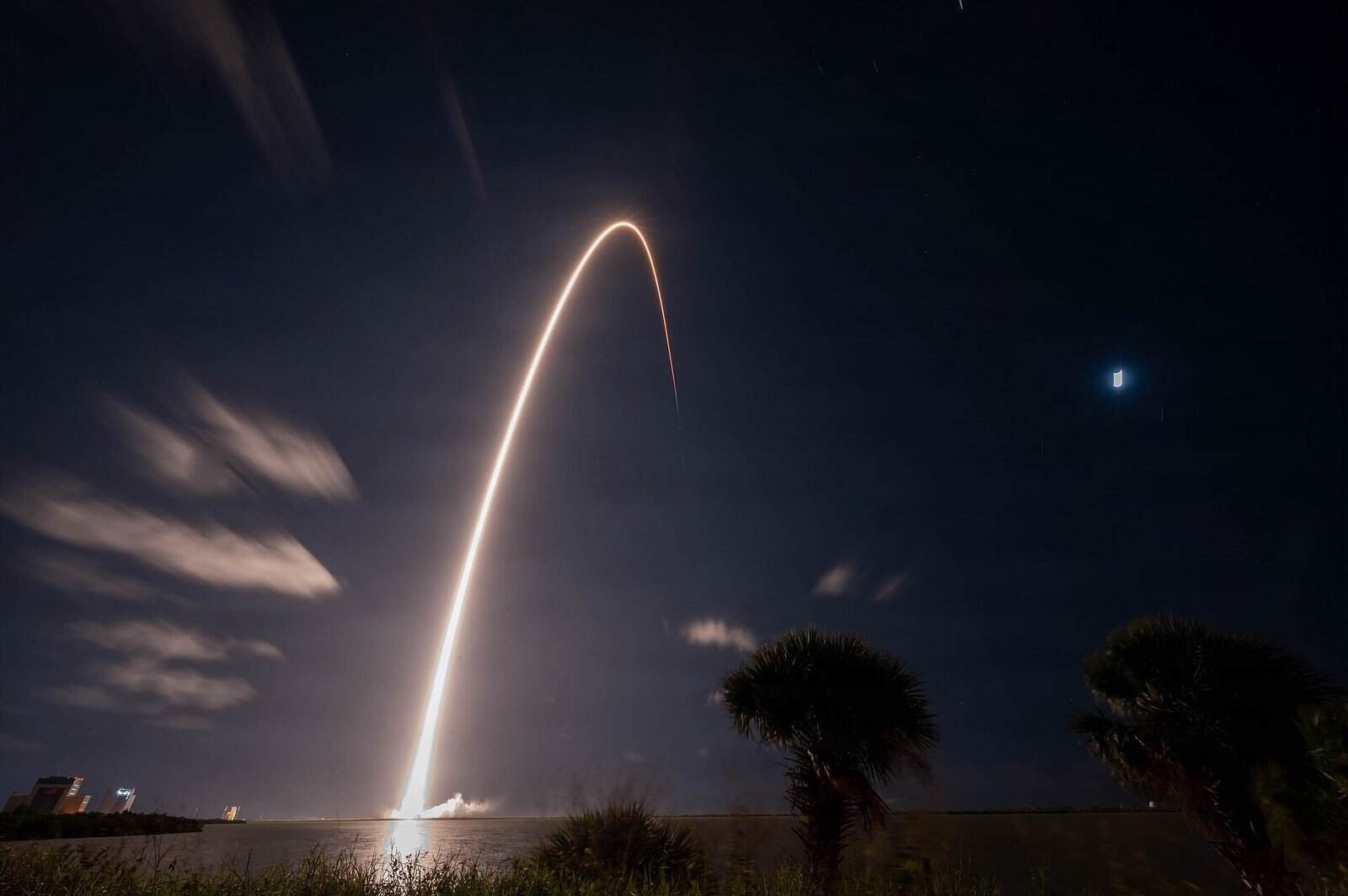 SpaceX Falcon 9 rocket launch arcing into the night sky over Cape Canaveral