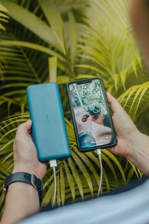 Black smartphone charging from a green portable power bank, close-up